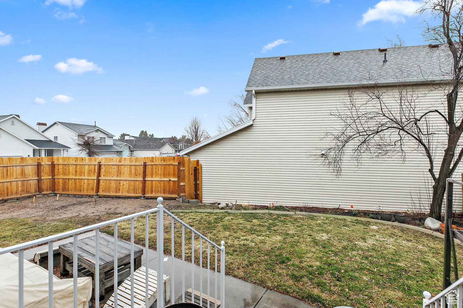 Expansive backyard featuring a new wood privacy fence, a concrete patio, and a sloped grassy area