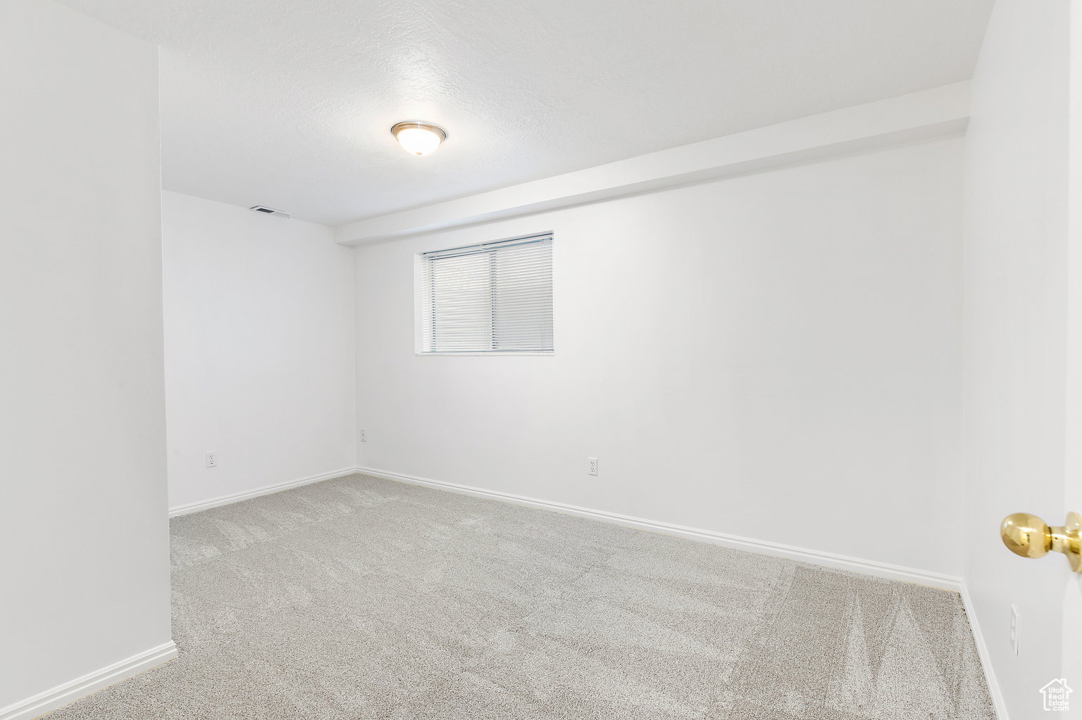Room with light-colored carpeting, white walls, and a window with horizontal blinds