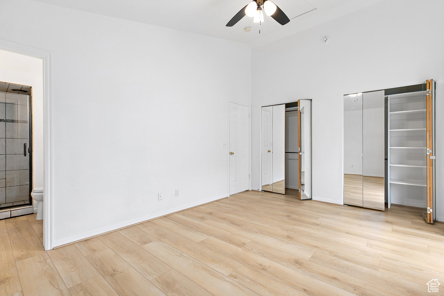 Spacious interior with wood-finish flooring, high ceilings, and a ceiling fan