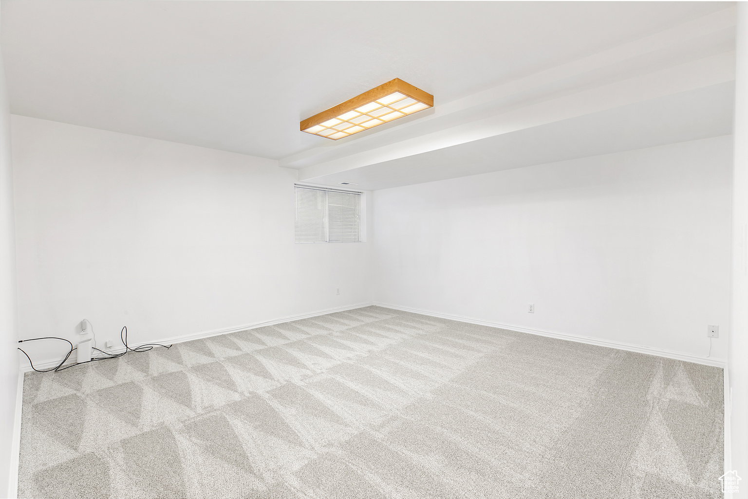 Spacious room featuring light gray patterned carpeting and white walls
