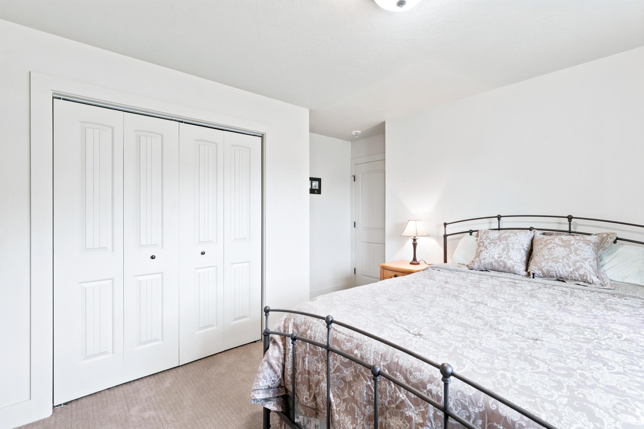 Carpeted bedroom featuring white walls, a flush-mount ceiling light, and white paneled bi-fold closet doors