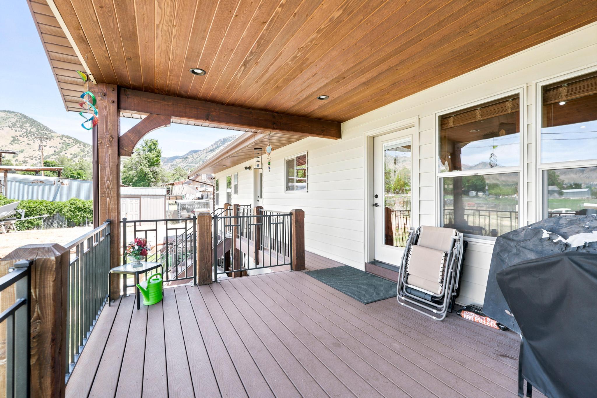 Spacious covered deck featuring a wood-finish ceiling with recessed lighting, composite decking, and decorative metal railings