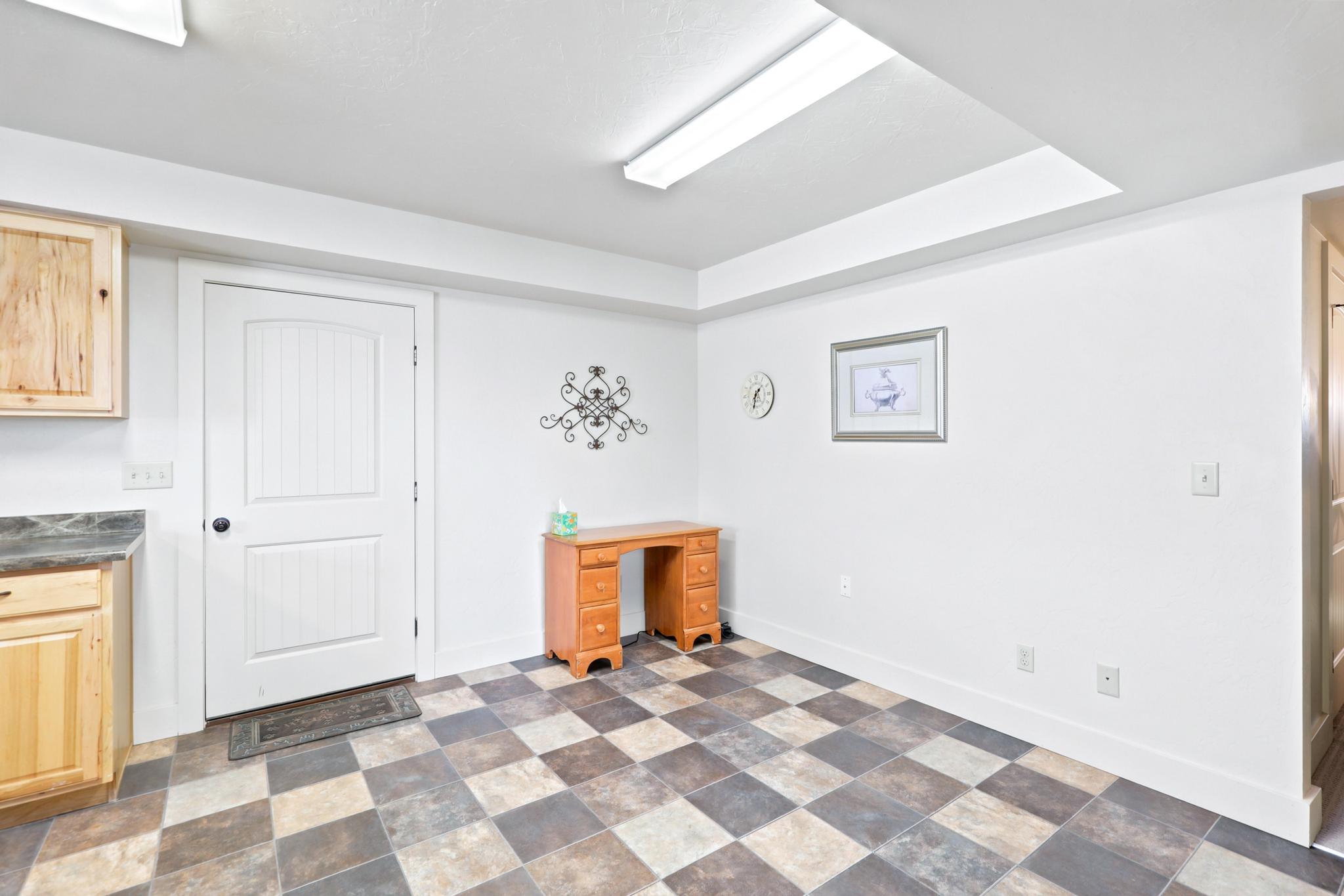 Spacious room featuring a checkerboard-patterned floor, white walls, and built-in wood cabinetry with a dark countertop
