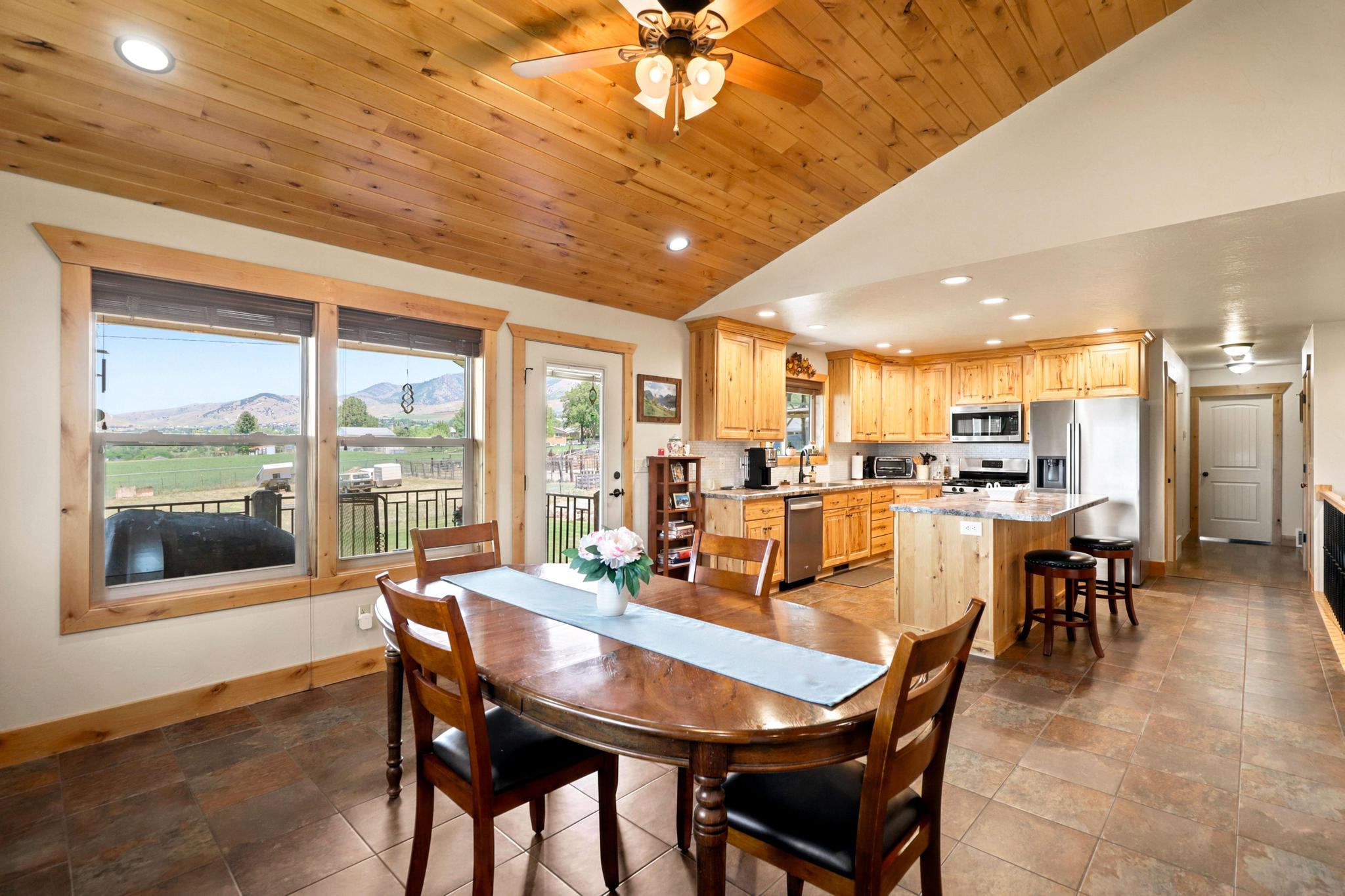 Open-concept kitchen and dining area featuring a vaulted wood-finish ceiling, recessed lighting, and large windows