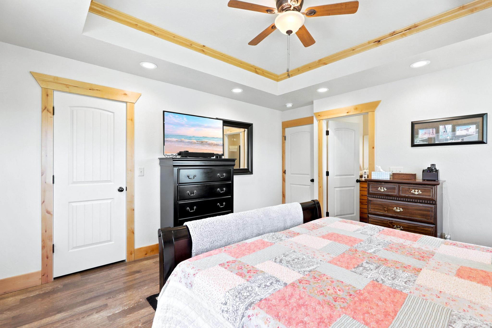 Spacious room featuring a tray ceiling with wood-finish trim, recessed lighting, and a ceiling fan
