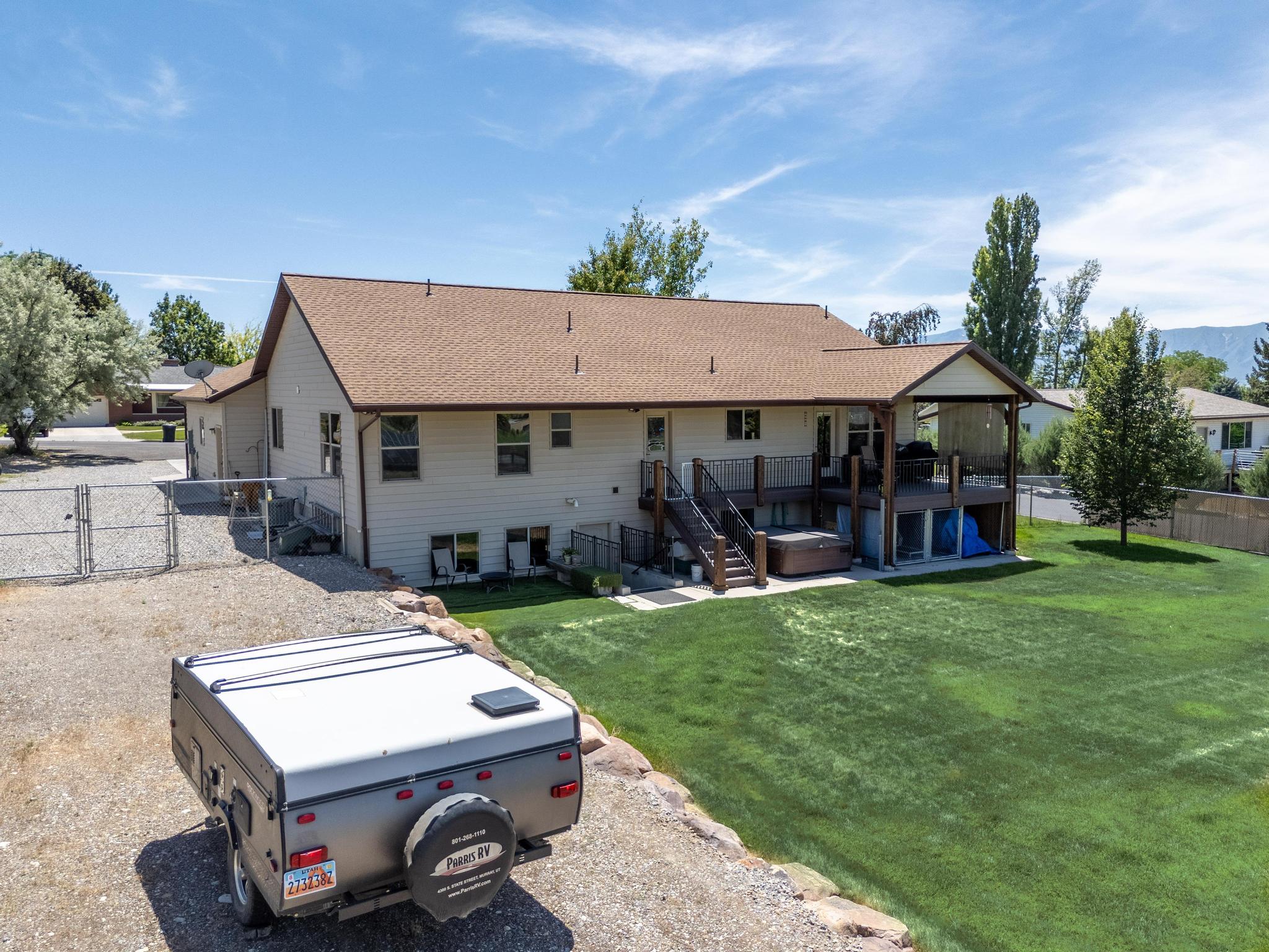 Expansive backyard featuring a manicured lawn, a multi-level deck with a covered portion, and an integrated hot tub