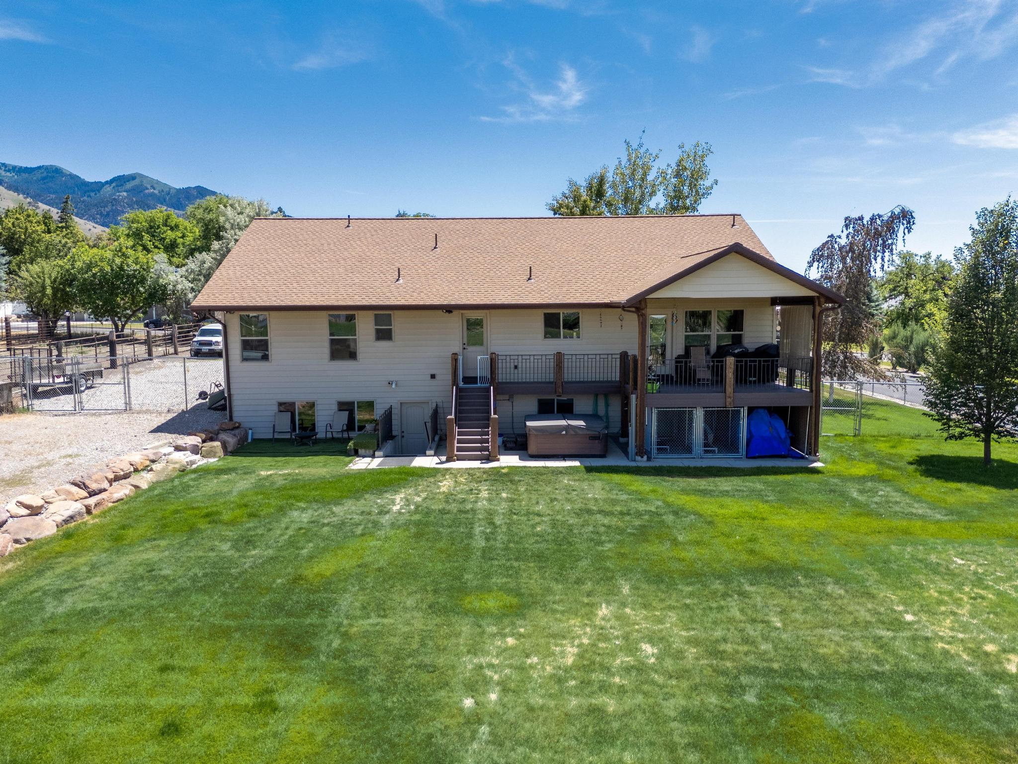 Expansive green lawn bordering a two-story residence with a multi-level deck