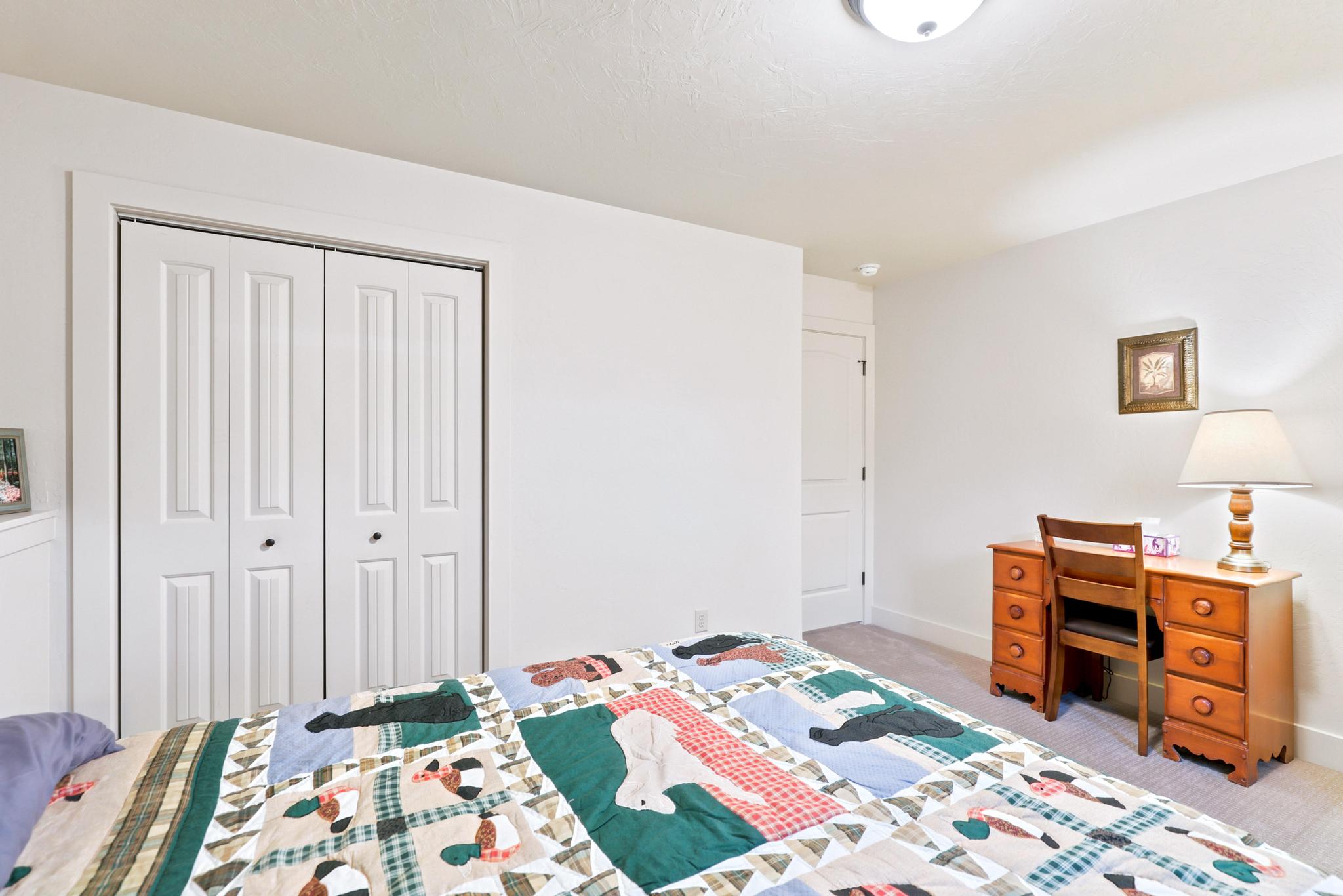White bi-fold closet doors with black hardware, neutral carpeting, and a flush-mount ceiling light fixture