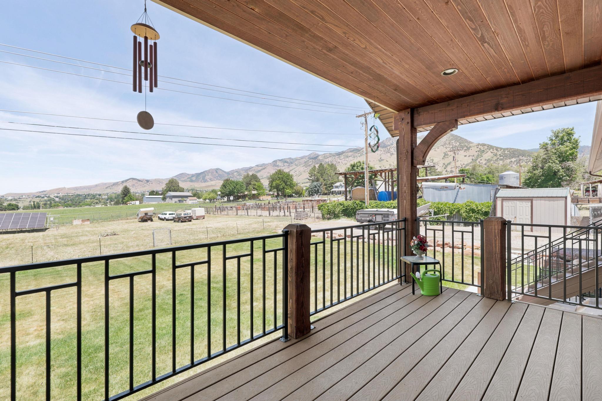 Covered outdoor deck with wood-finish decking, black metal railings, and a wood-paneled ceiling