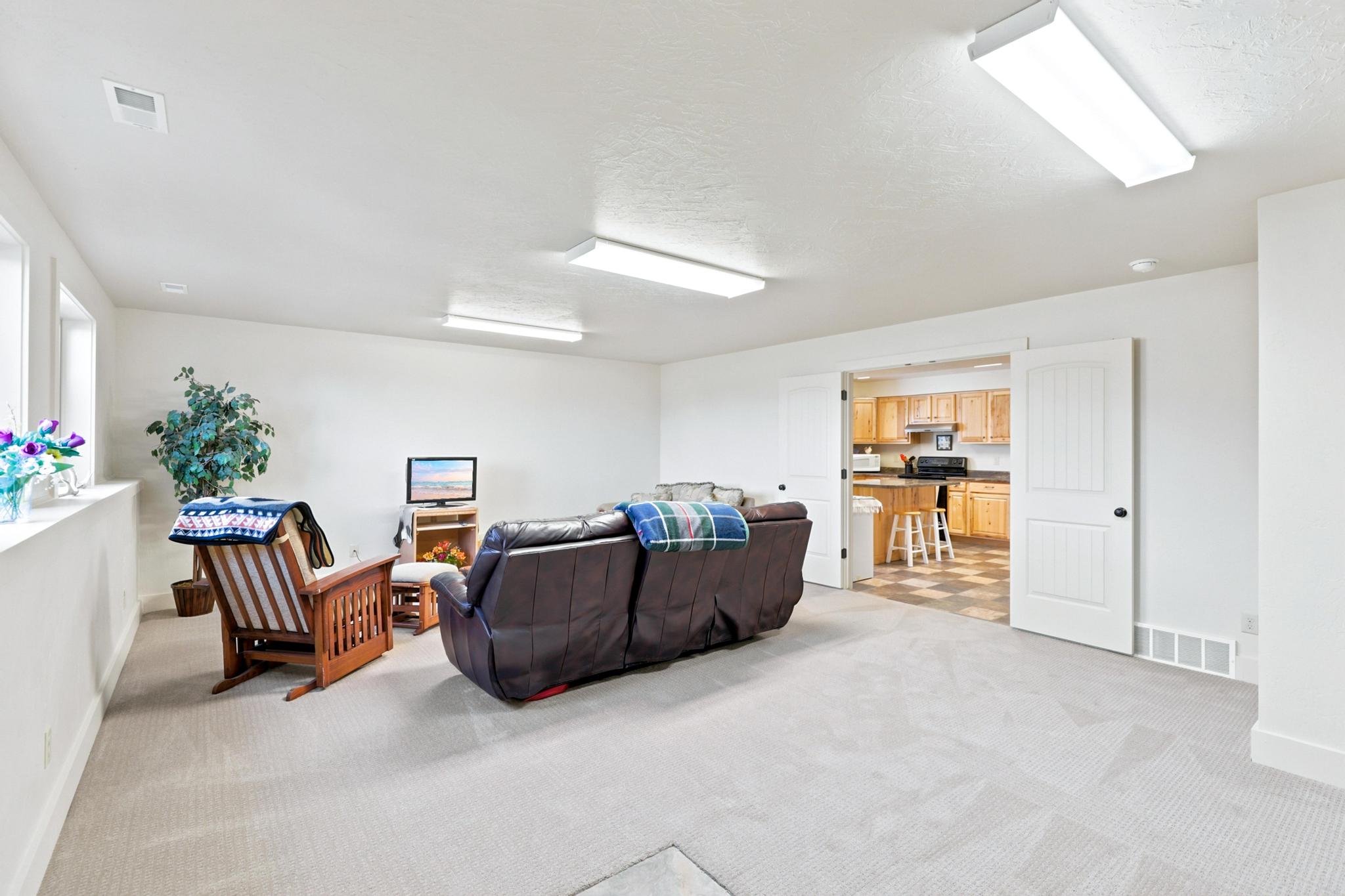 Spacious carpeted room featuring white walls and multiple windows