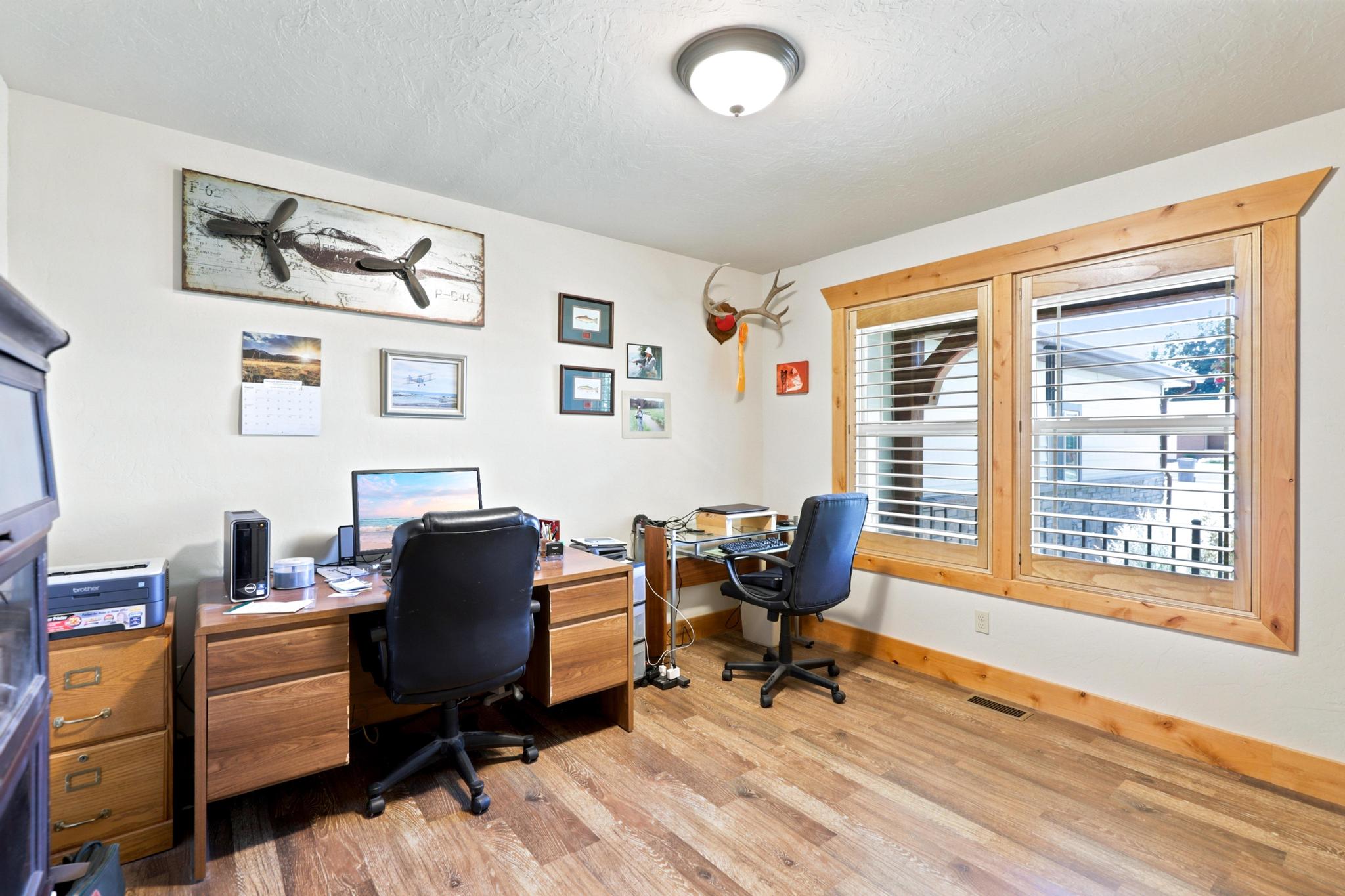 Room featuring wood-finish flooring, white walls, and natural wood trim around windows