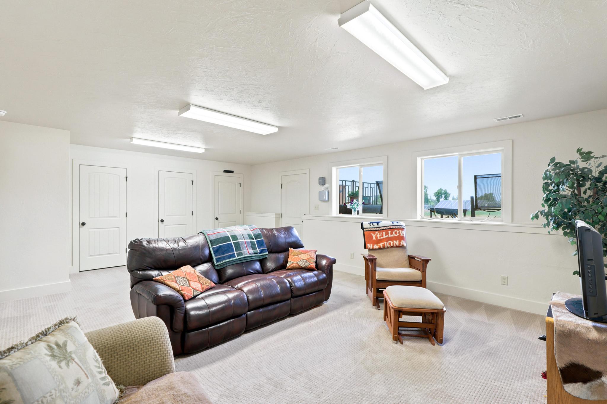 Spacious room featuring carpet flooring, multiple white paneled doors, and two horizontal windows providing natural light