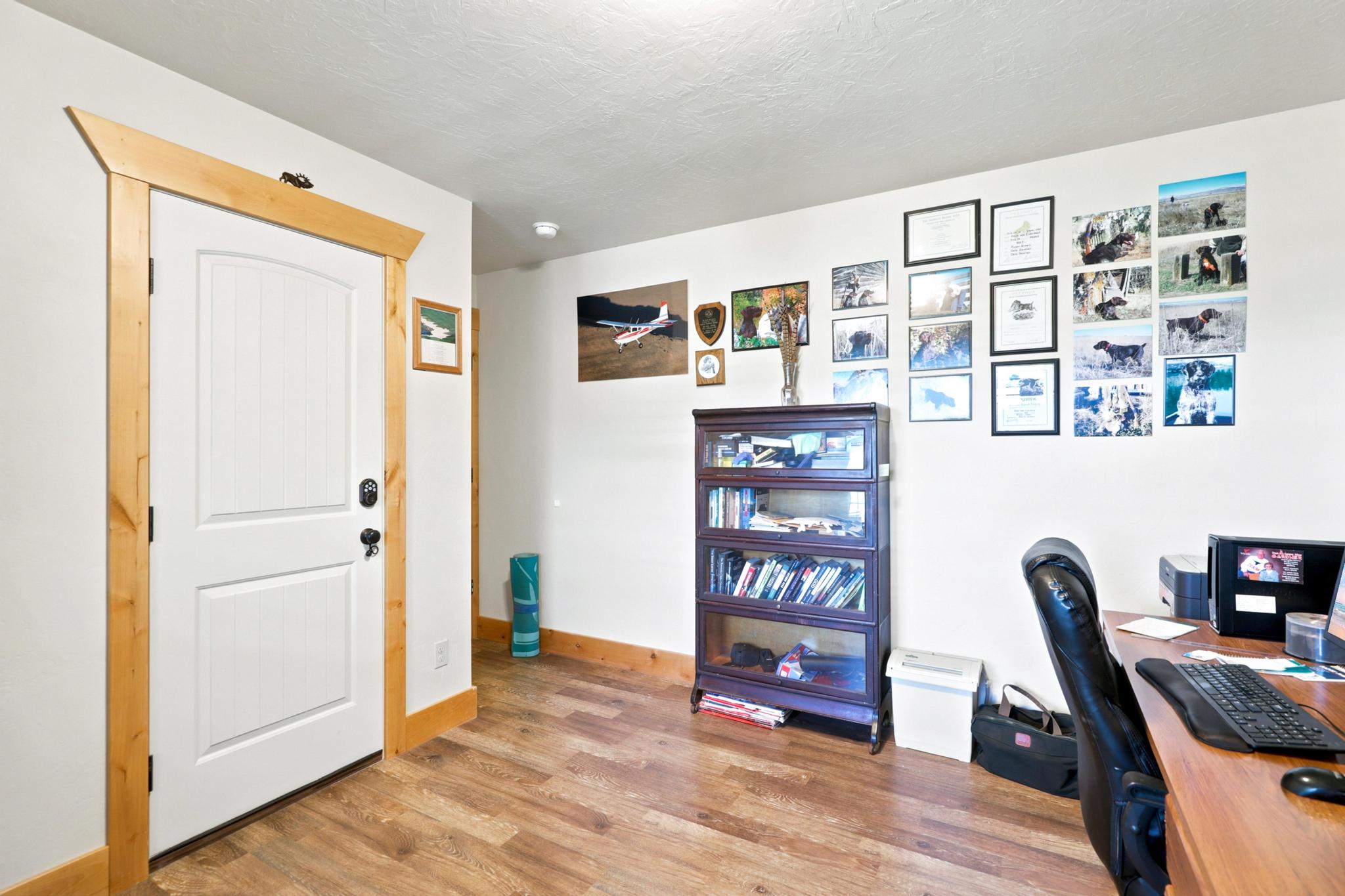 White paneled door with natural wood trim, wood-finish flooring, and crisp white walls