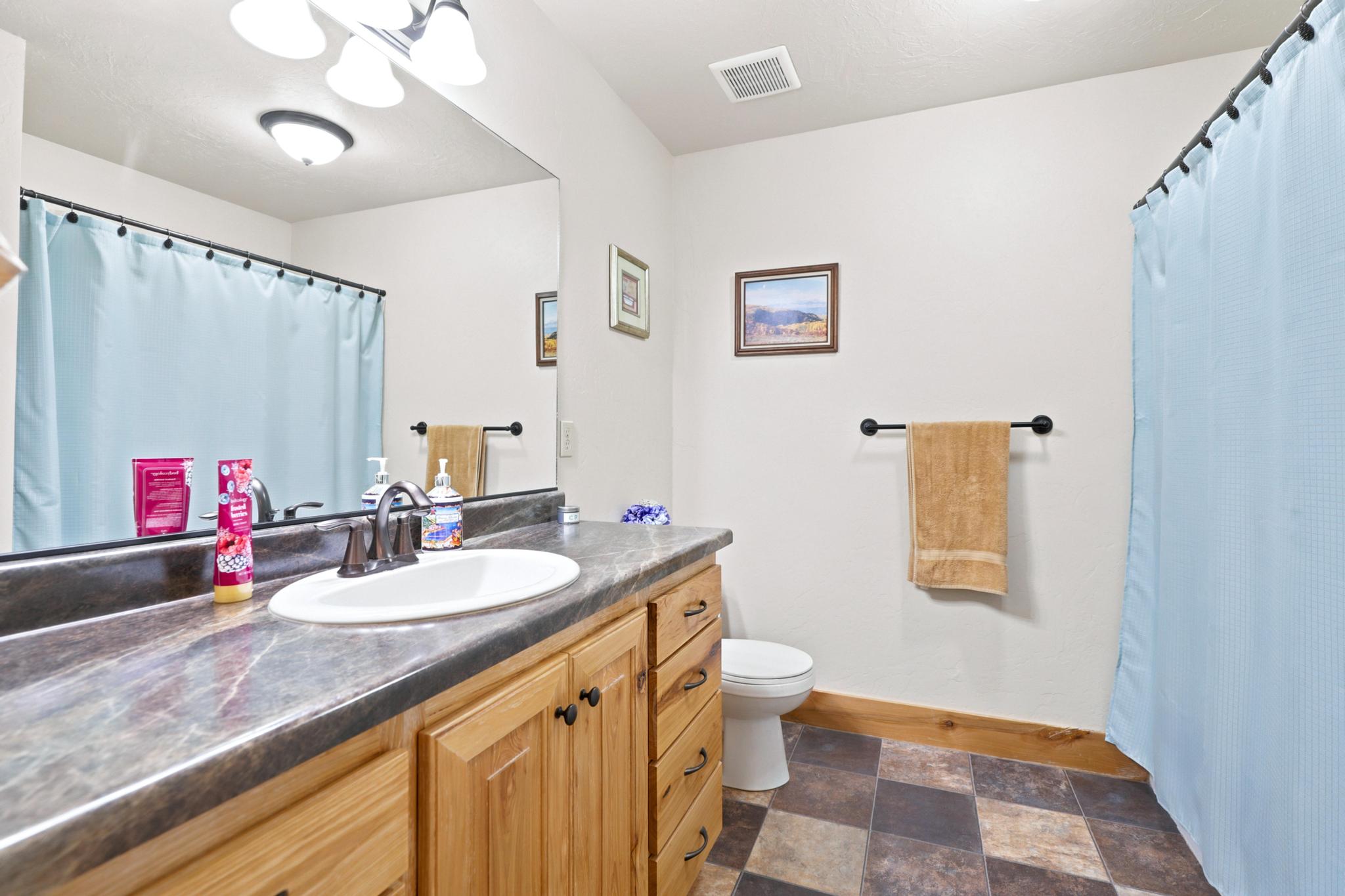Bathroom vanity with a single basin sink, bronze-finish faucet, and a large wall-mounted mirror