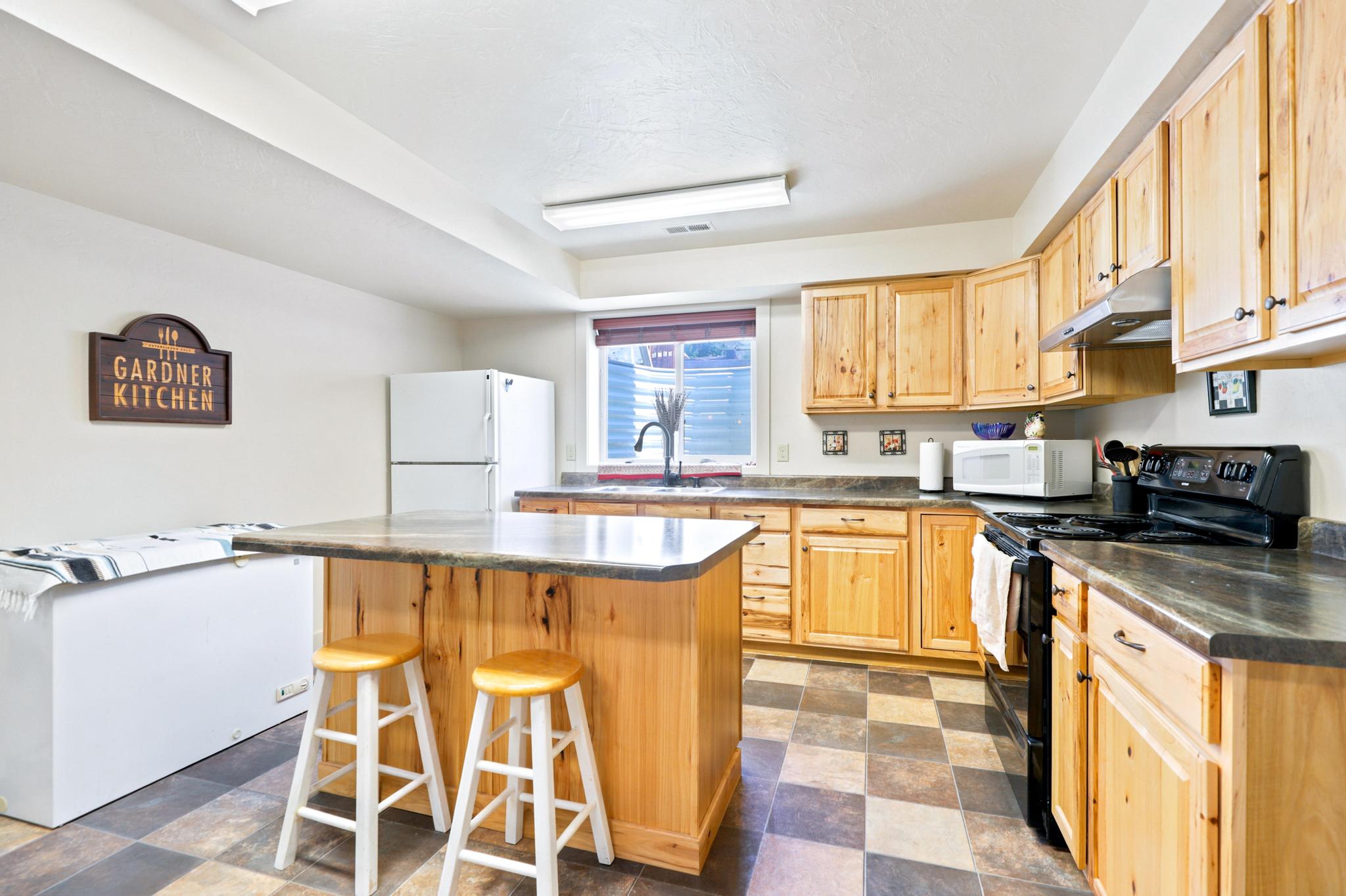 Kitchen featuring knotty pine cabinetry, a central island with bar seating, solid surface countertops, and checkered pattern flooring