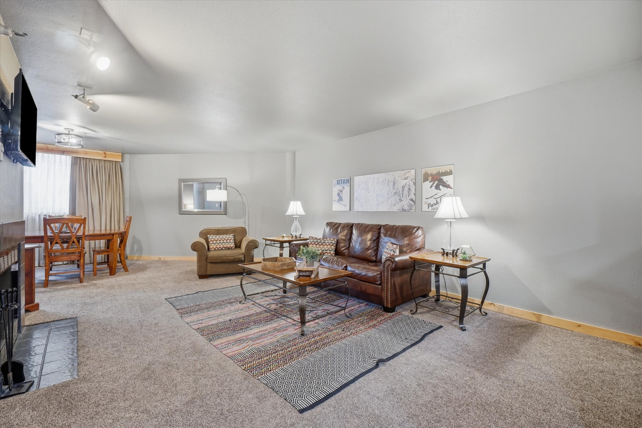 Carpeted living area featuring light gray walls, wood trim, and a window with neutral drapes