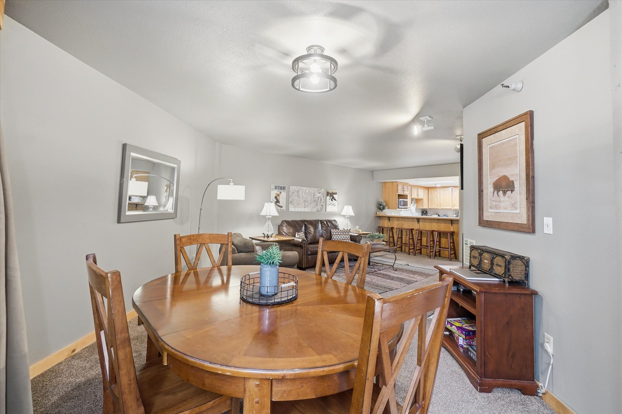 Open concept living area featuring neutral wall tones, recessed lighting, carpet flooring, a breakfast bar, and a dining area with wood-finish flooring