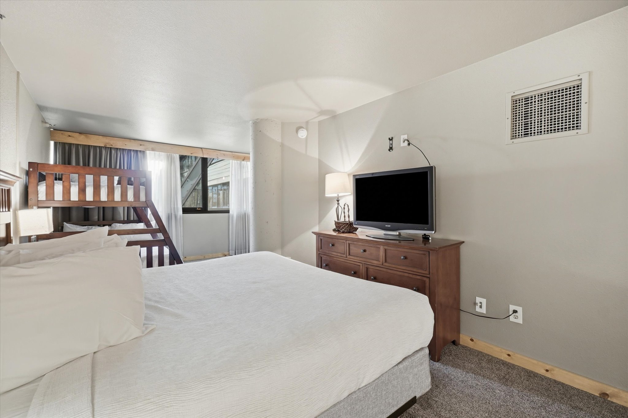 Carpeted bedroom with a built-in bunk bed, a window with curtains, and light gray walls