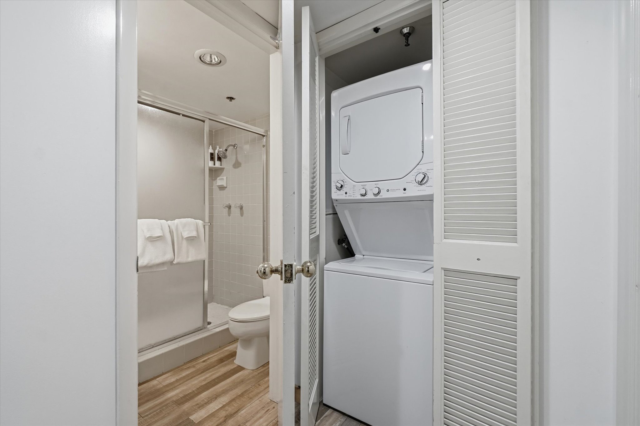 Compact laundry area featuring a stackable washer and dryer, situated within a louvered bi-fold closet