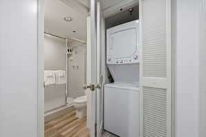 Compact laundry area featuring a stackable washer and dryer, situated within a louvered bi-fold closet