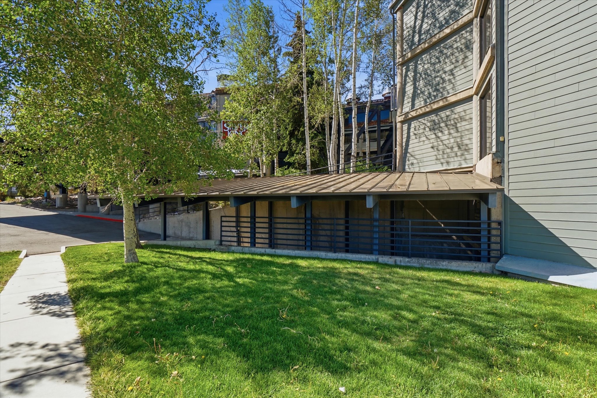 Exterior featuring covered parking structure, horizontal siding, and mature trees