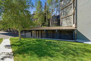 Exterior featuring covered parking structure, horizontal siding, and mature trees