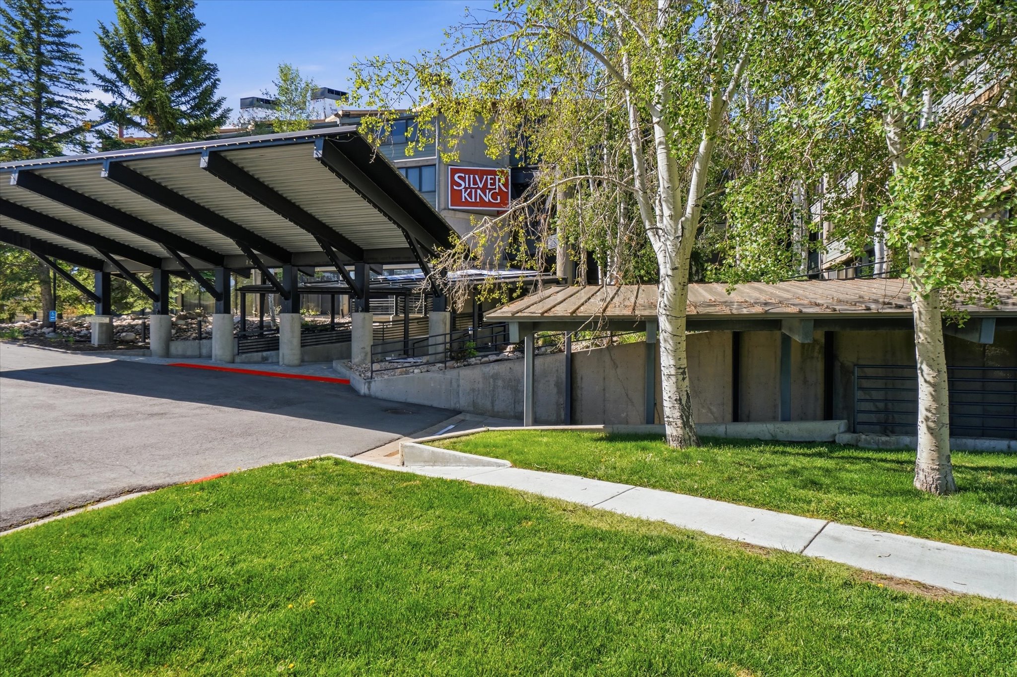Covered entrance with a multi-level concrete and asphalt driveway