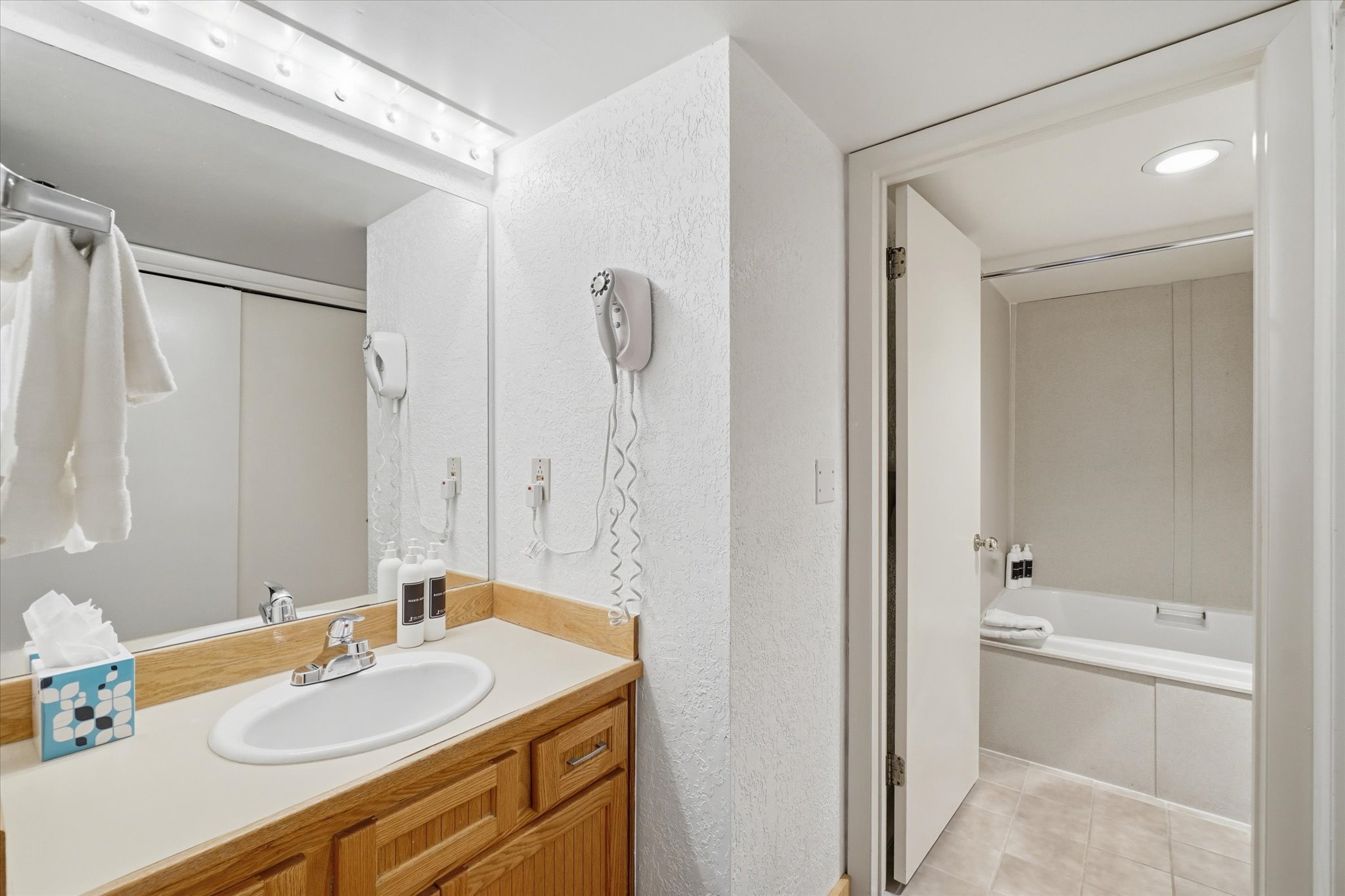 Bathroom vanity featuring a light wood cabinet with an integrated white oval sink and a light-toned countertop