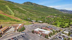 Expansive aerial perspective showcasing a mountainous landscape with ski slopes, a golf course, and multiple buildings