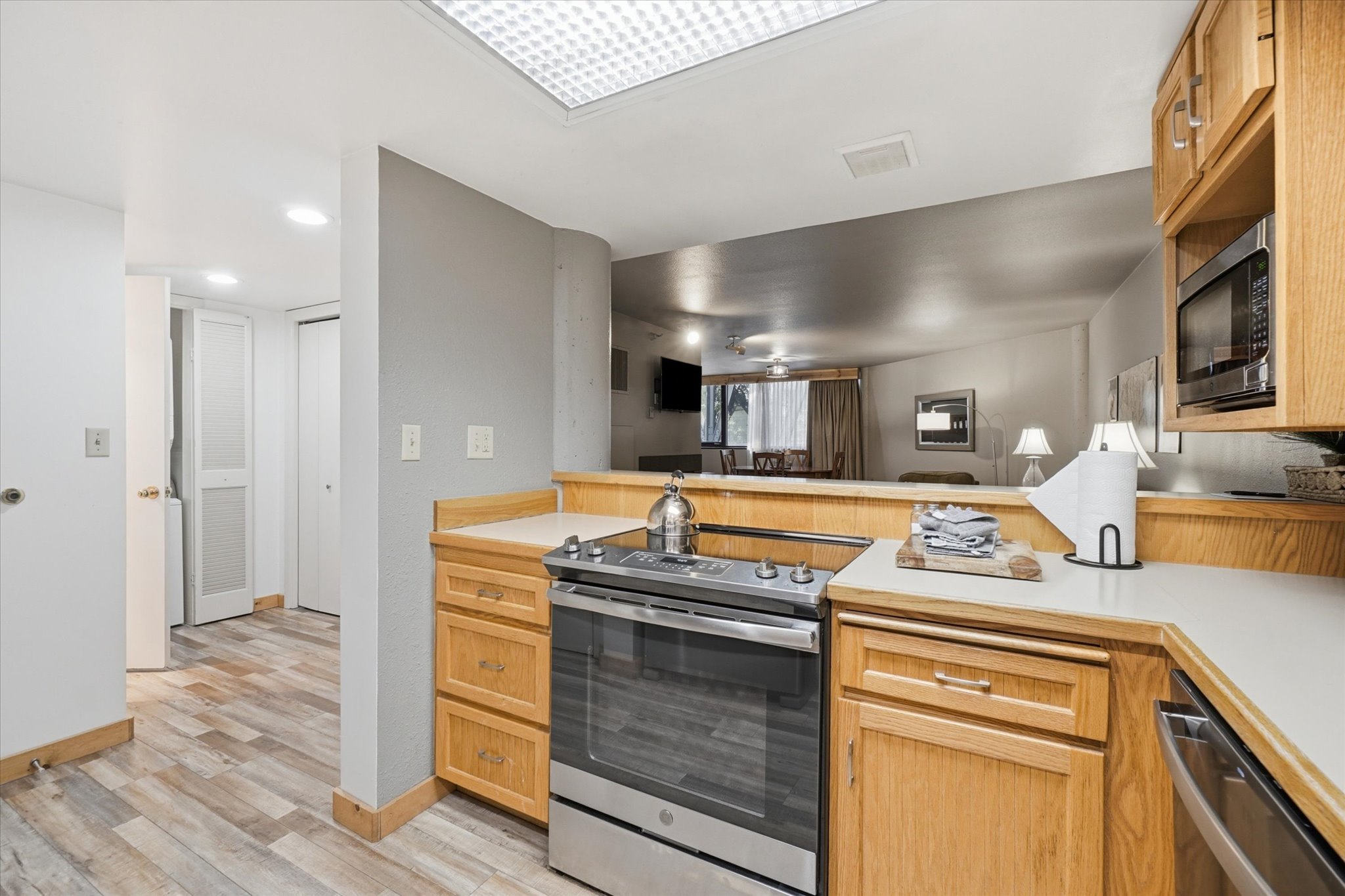 Kitchen featuring wood-finish flooring, light wood cabinetry, white countertops, and a stainless steel range