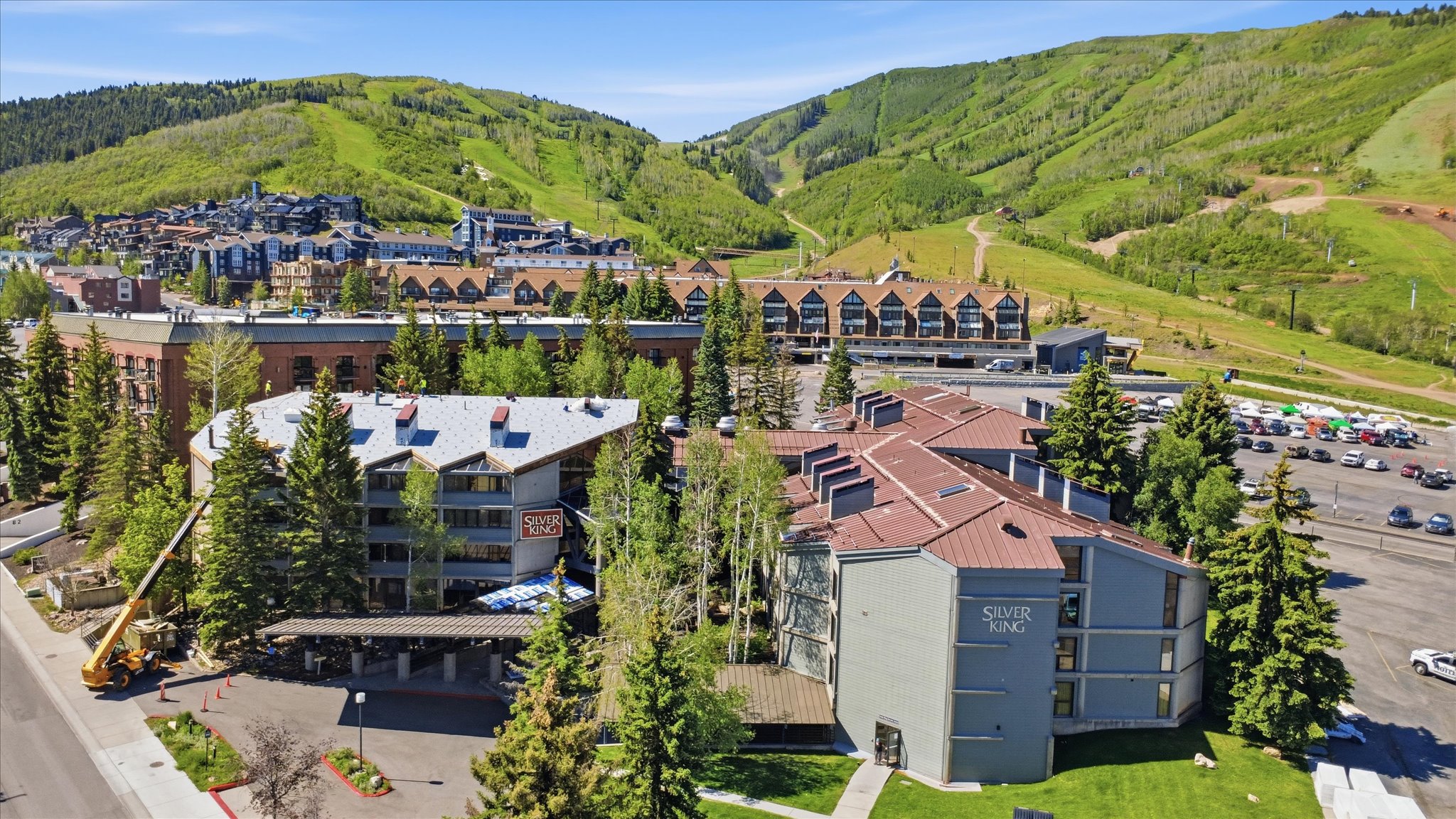 Expansive property featuring multiple buildings with gabled roofs, natural green landscaping, and surrounding mountainous terrain