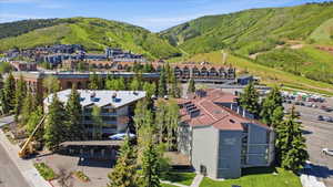 Expansive property featuring multiple buildings with gabled roofs, natural green landscaping, and surrounding mountainous terrain