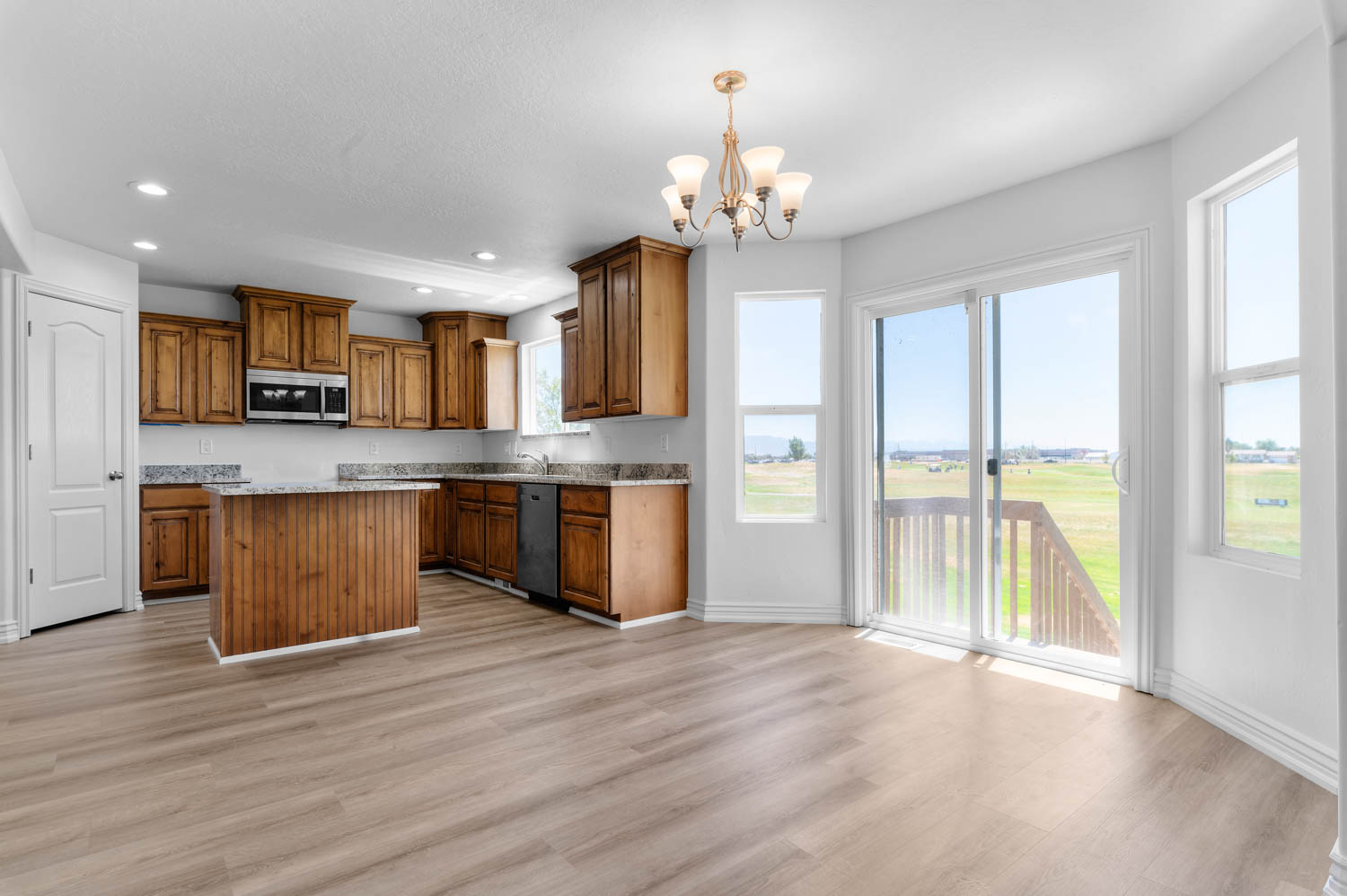 Open-concept kitchen and dining area featuring wood-finish flooring, recessed lighting, and a chandelier