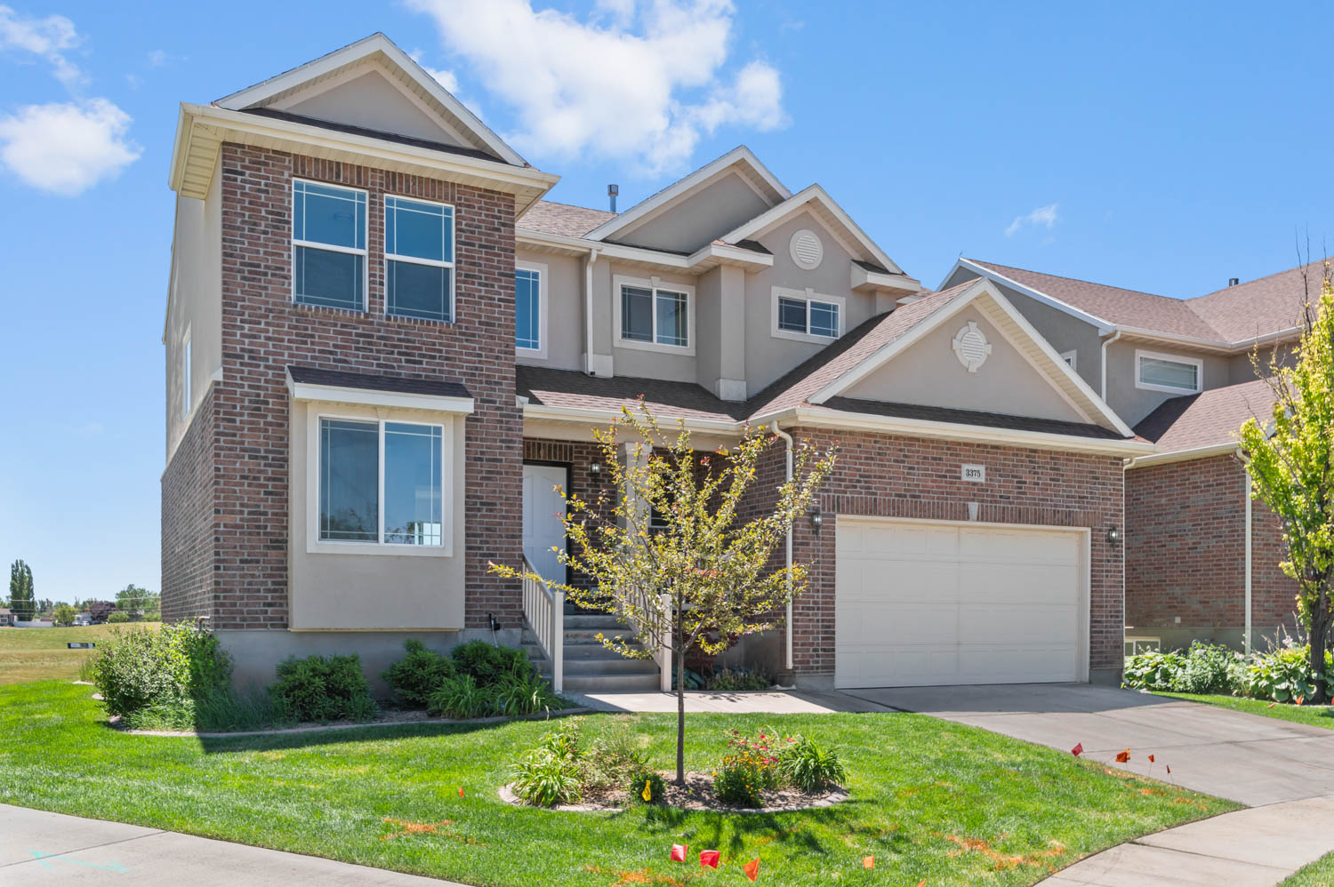 Brick and stucco exterior featuring multiple gables, an integrated garage, and a covered entry