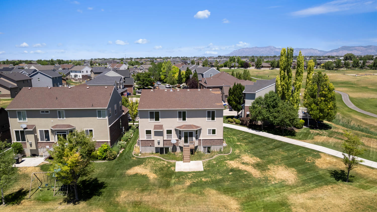 Rear exterior featuring a two-story design with a walk-out basement, light-colored siding, and a brown shingle roof