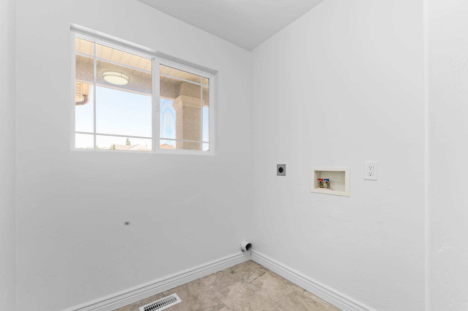 Laundry area with a grid-pattern window, neutral-toned flooring, white baseboards, and appliance hookups