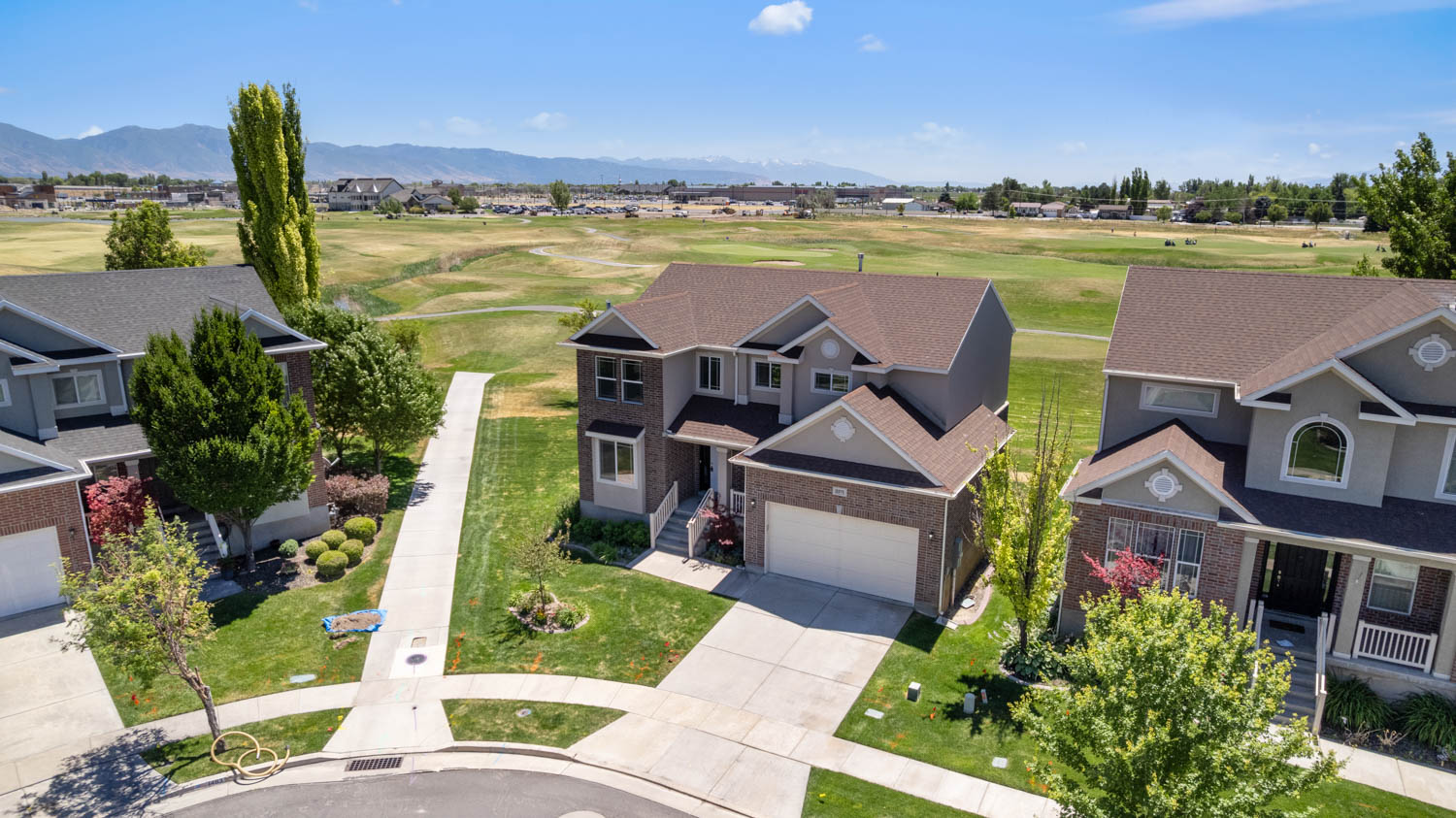 Two-story residence featuring a brick and siding exterior, front-facing garage, concrete driveway, and established landscaping