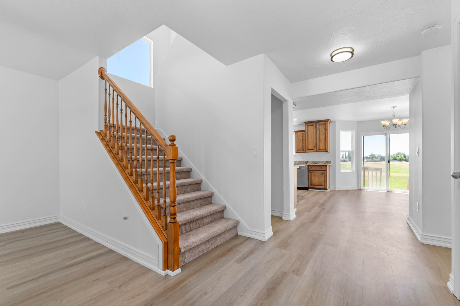 Staircase featuring wood balusters and a carpeted tread, set against light-toned wood-finish flooring
