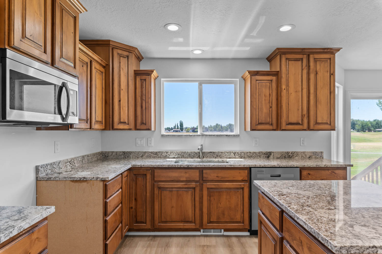 Kitchen featuring wood cabinetry, light-toned granite countertops, and stainless steel appliances