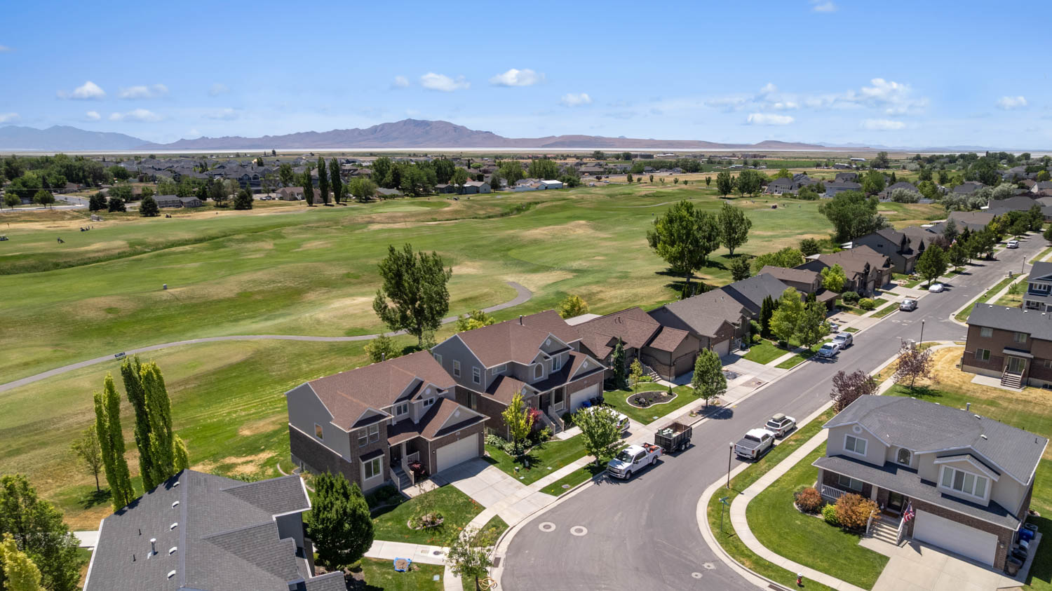 Residential neighborhood featuring a golf course, mature trees, and mountain backdrop