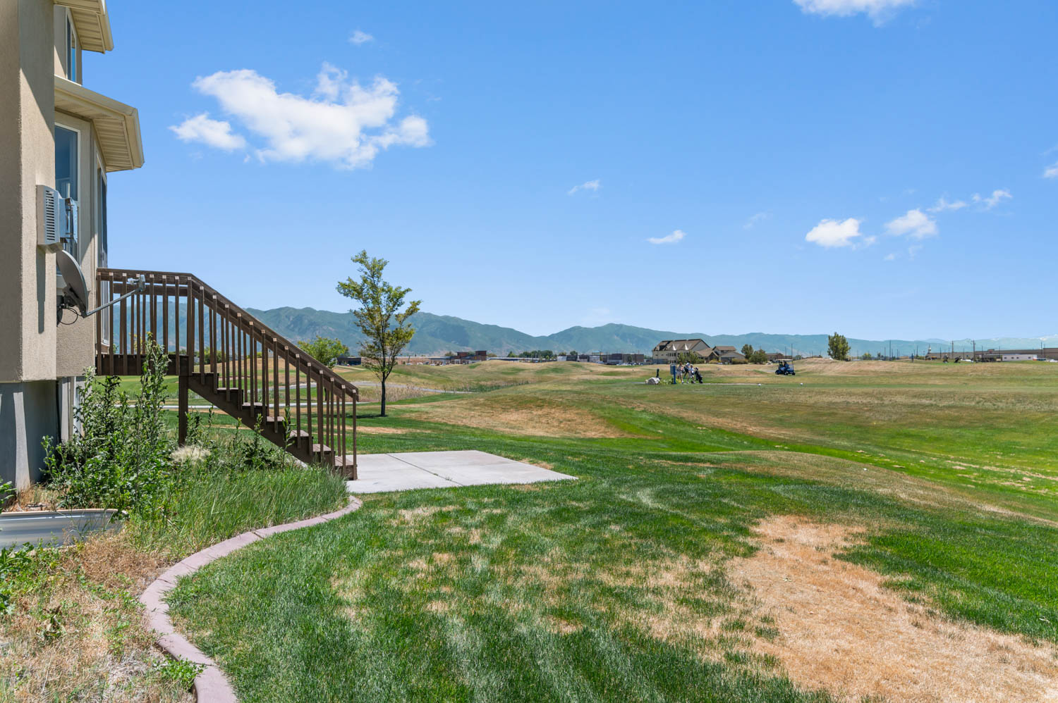Expansive backyard featuring a manicured lawn, concrete patio, and direct access to open green space