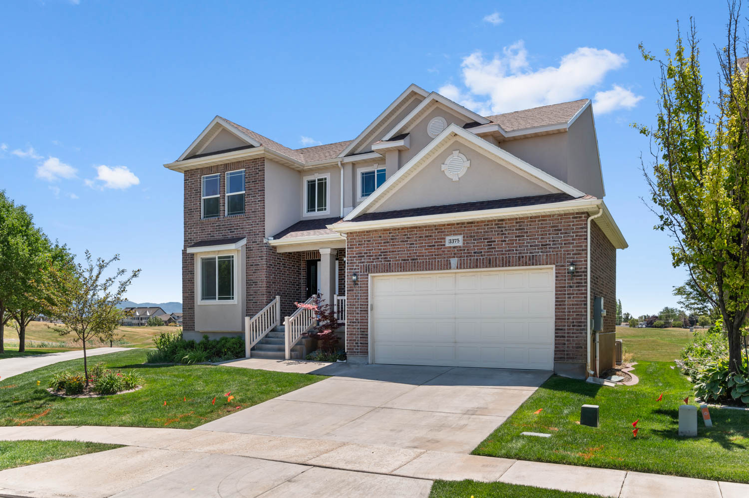 Two-story residence featuring a brick and stucco exterior, an attached two-car garage, and a concrete driveway