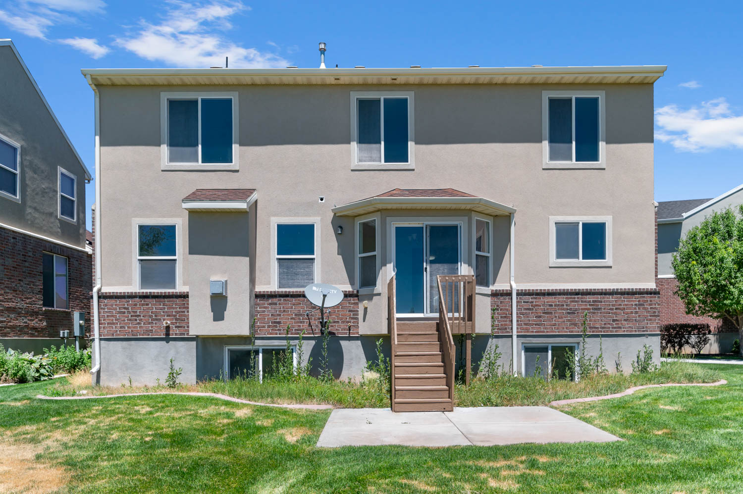 Rear exterior showcasing a two-story stucco and brick facade with multiple windows