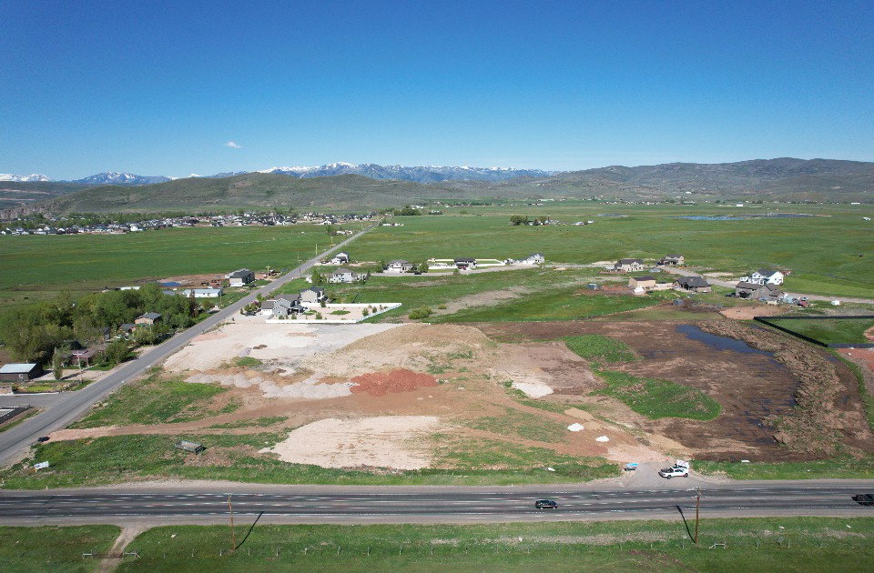 Expansive undeveloped land featuring a cleared building site, direct road frontage, and distant mountain scenery