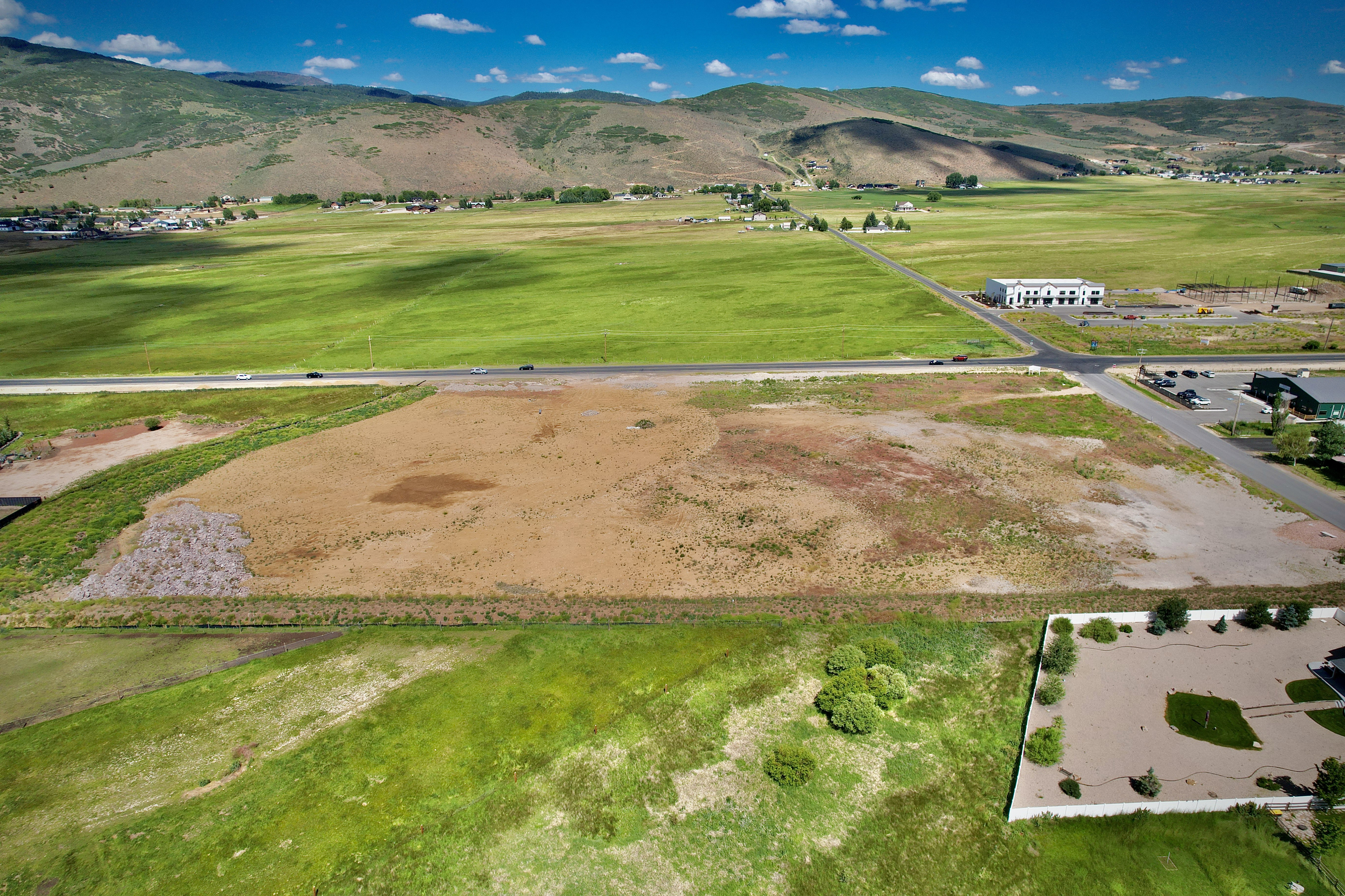 Expansive land parcel featuring a road frontage, a varied topography with both cleared and vegetated sections, and distant mountainous terrain
