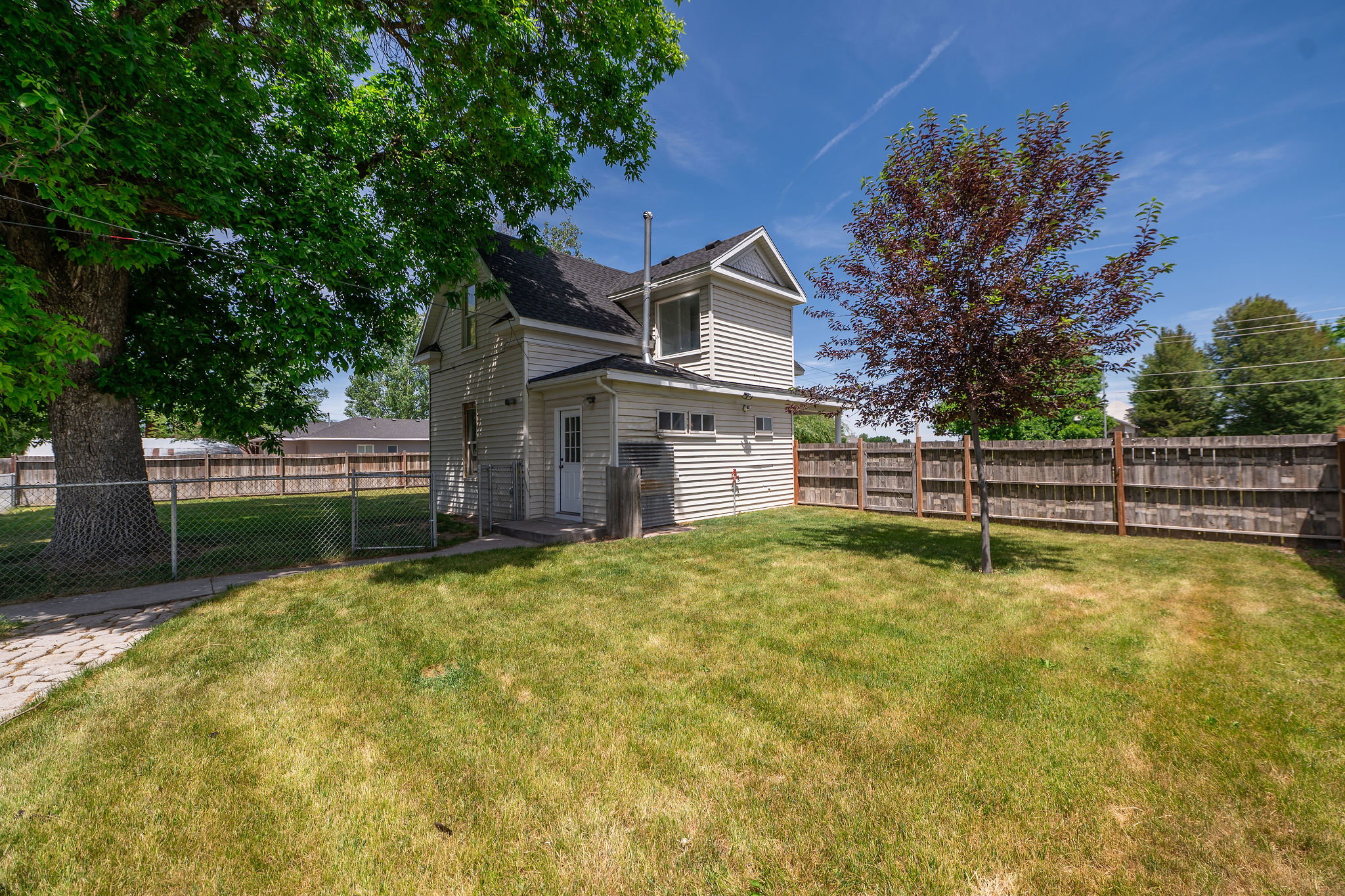 Expansive backyard featuring a manicured lawn, a chain-link fence, and a privacy fence
