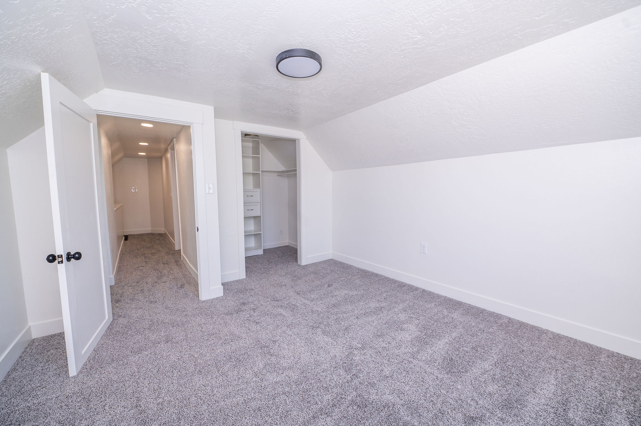Carpeted room featuring a sloped ceiling and recessed lighting in the hallway