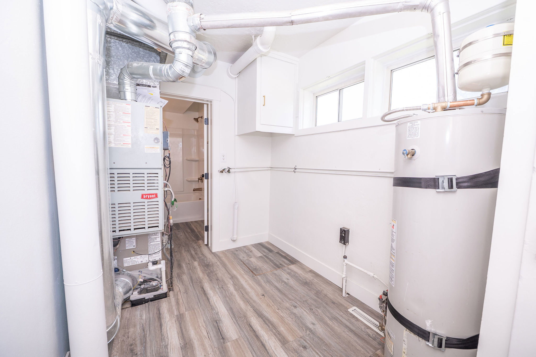 Utility room featuring wood-finish flooring, white walls, and two windows providing natural light
