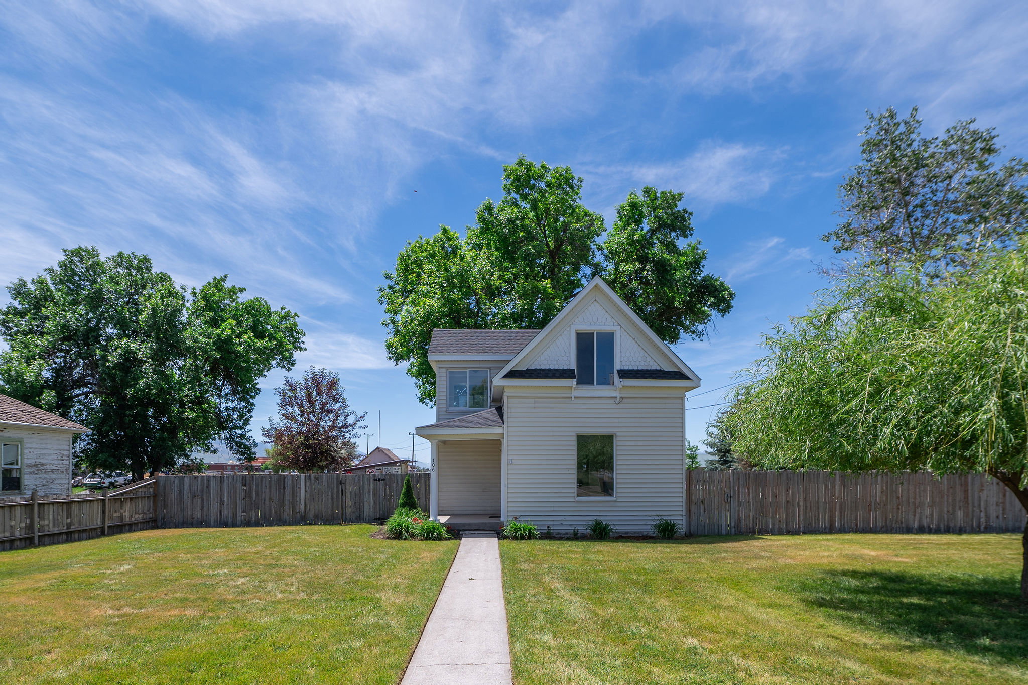 Traditional-style home featuring white siding and a prominent gable with double windows