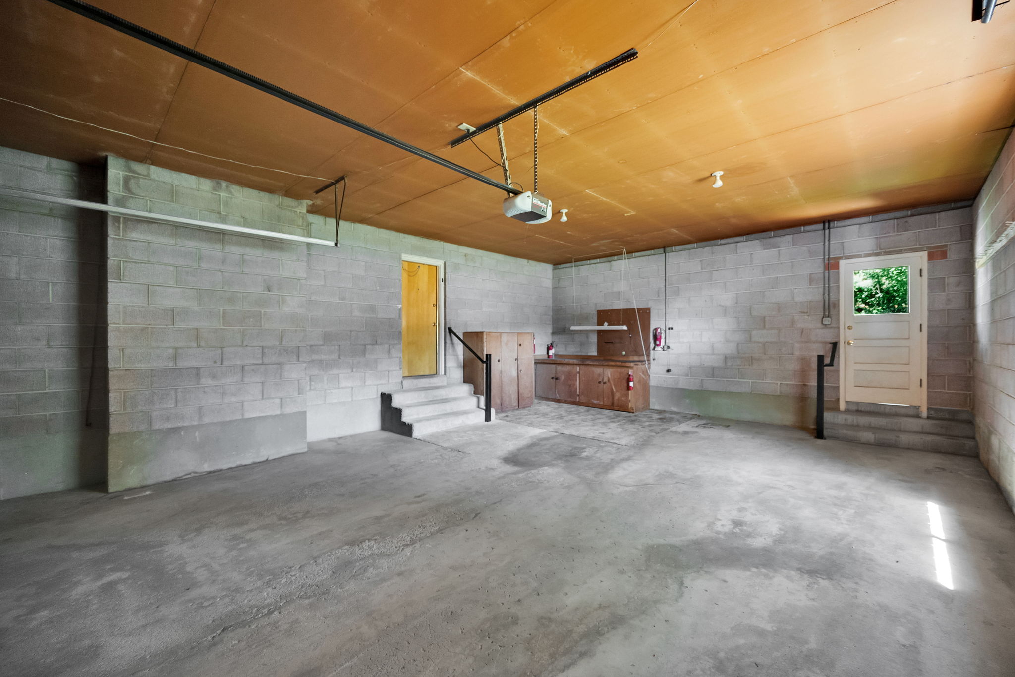 Spacious garage with concrete block walls, concrete flooring, built-in wooden cabinetry